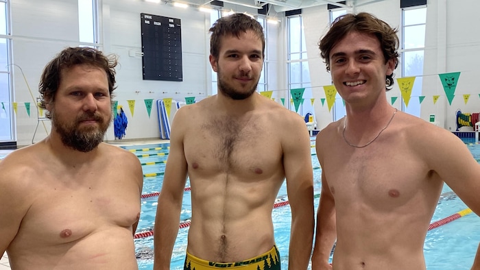 Trois hommes devant une piscine.