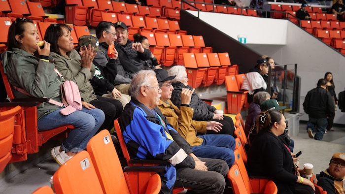 Des spectateurs assis dans un aréna regardent une partie de hockey.