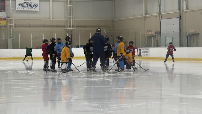 Des jeunes sur la glace qui discutent avec leur entraîneur.