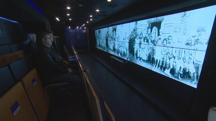 Personnes assises dans un autobus transformé temporairement en salle de projection. 