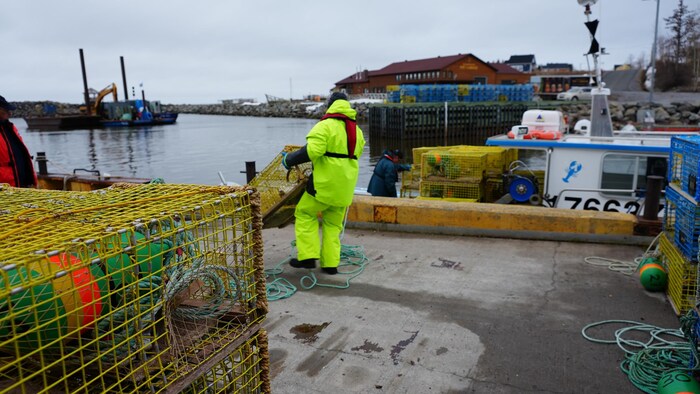 Un homme qui s'apprête à embarquer un casier à bord d'un bateau.