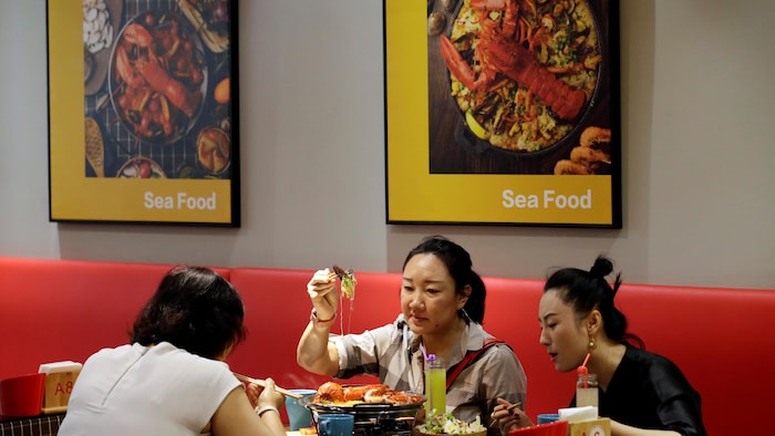 Trois femmes autour d'un repas de homard dans un restaurant de fruits de mer en Chine.