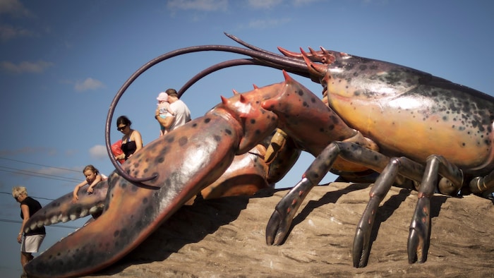 Des gens grimpés sur une sculpture de homard géante.