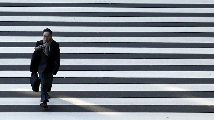 Un homme d'affaires traverse une rue à Tokyo.
