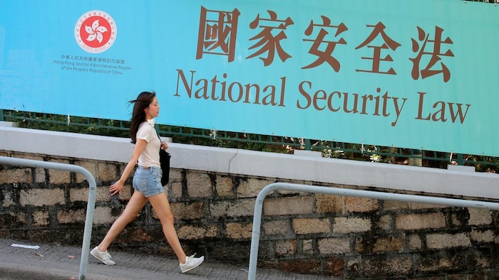 Une femme passe devant une bannière promotionnelle de la loi sur la sécurité nationale pour Hong Kong.