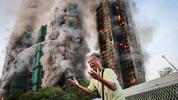 Un homme crie au désespoir devant les tours d'habitation en feu.