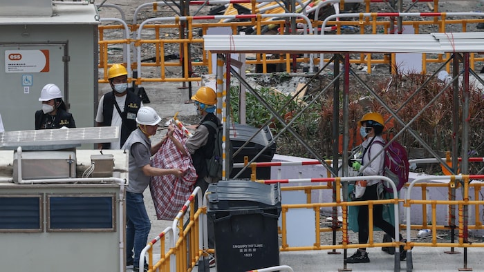Des résidents transportent des effets personnels récupérés au complexe d'appartements Wang Fuk Court lors de leur première visite sur les lieux, le 20 avril 2026.
