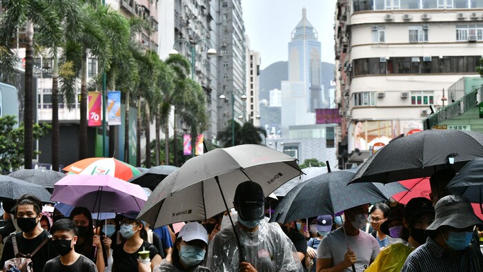 Des personnes participent à une marche de protestation et tiennent des parapluies en raison du mauvais temps.