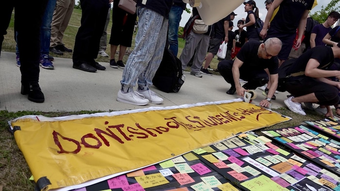 Des personnes préparent des banderoles de manifestations, dont une mentionne en anglais «ne tirez pas sur les étudiants».