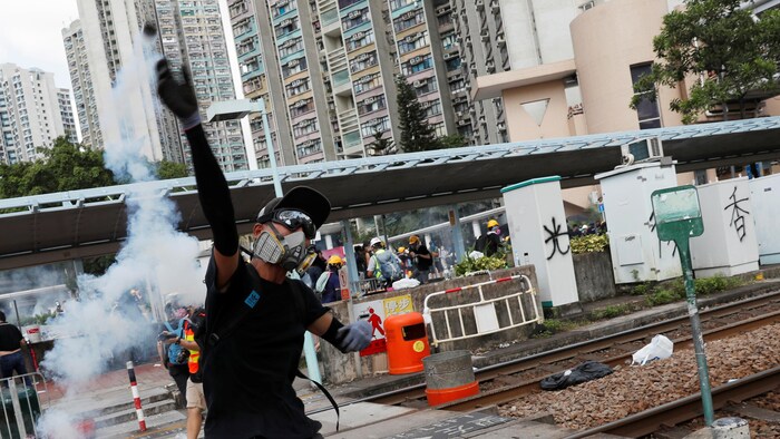 Un manifestant muni d'un masque à gaz renvoie une grenade lacrymogène vers la police dans une gare de Hong Kong.