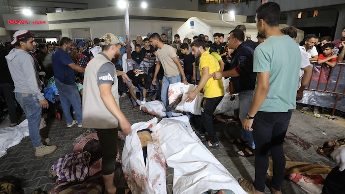 Dans un hôpital, des personnes sont rassemblées autour des corps de Palestiniens tués lors d'une attaque dans un autre hôpital de Gaza.