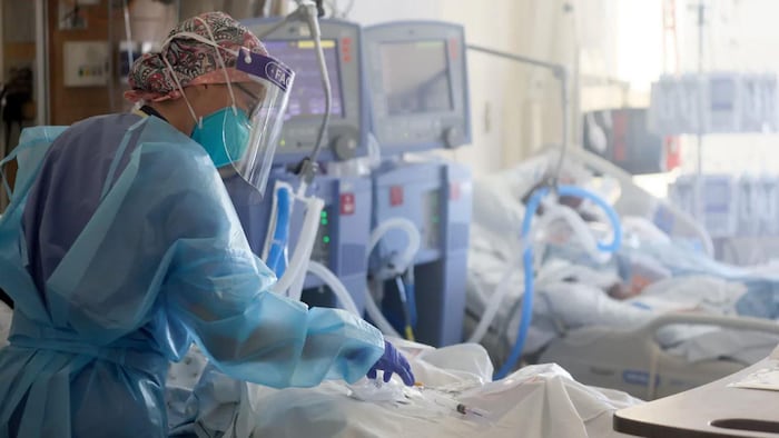 Une infirmière se penche sur un patient atteint de la COVID-19 à l'hôpital.