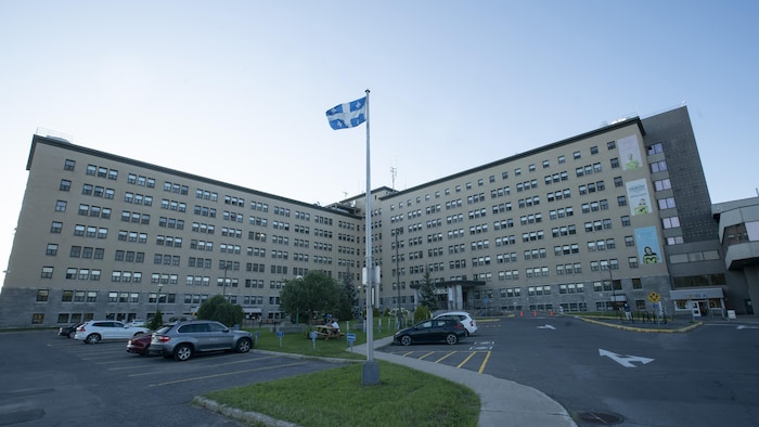 L'entrée principale de l'hôpital de Joliette, devant laquelle se trouve un stationnement. Un drapeau du Québec flotte au-dessus du stationnement.