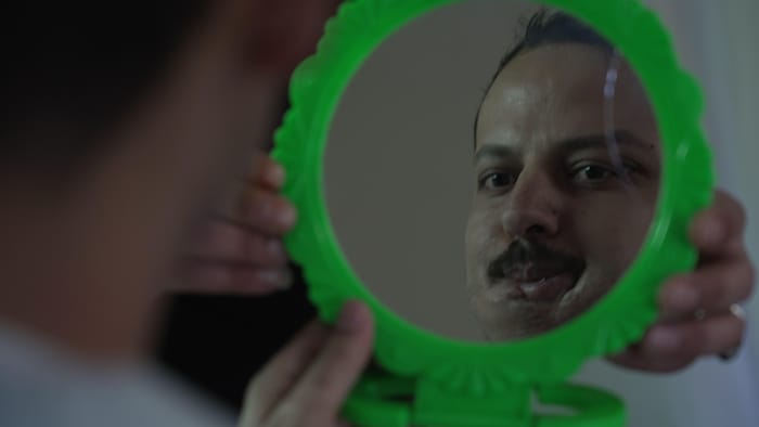 L'homme se regarde dans un miroir.