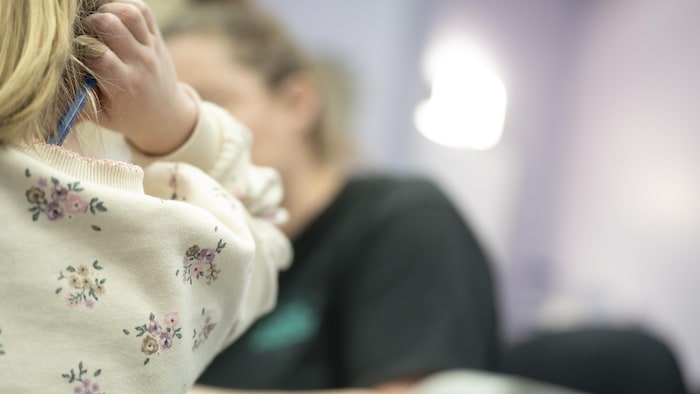 Une main d'enfant, avec en arrière-plan un adulte.