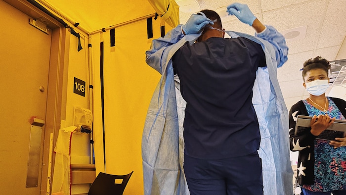Une employé de l'hôpital de Sept-Îles revêt son habit de protection.