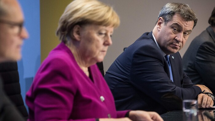 Les trois sont assis et M. Müller est tourné vers Mme Merkel.
