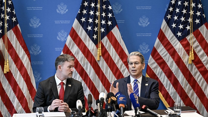 Ils sont assis devant des drapeaux américains.