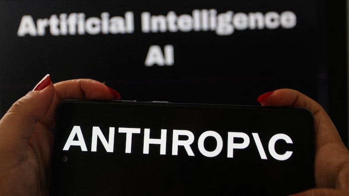 Au premier plan, on aperçoit un téléphone intelligent arborant le logo d'Anthropic.