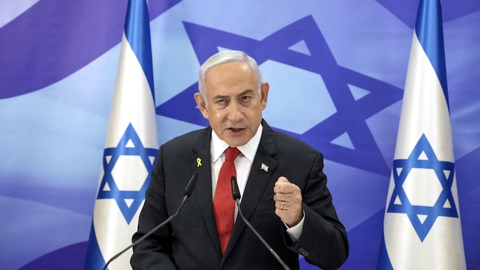 Benyamin Nétayahou parle dans deux micros avec lui une image du drapeau israélien. 