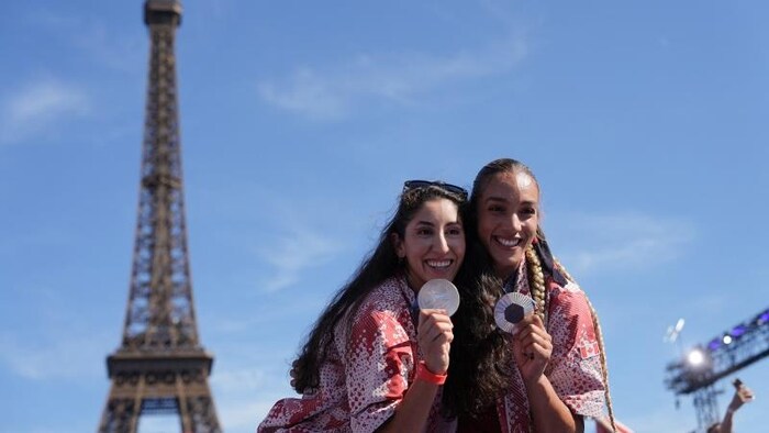 Melissa Humaña-Paredes (à gauche) et Brandie Wilkerson ont fêté la médaille d'argent en beach-volley aux Jeux olympiques de Paris 2024 le 10 août. Melissa est la fille du sociologue, entraîneur et joueur professionnel de volley-ball Hernán Humaña, qui s'est réfugié au Canada en 1980, fuyant la dictature au Chili. 