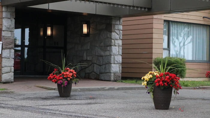 L'entrée de l'hôtel, avec des pots de fleurs et les lumières allumées.