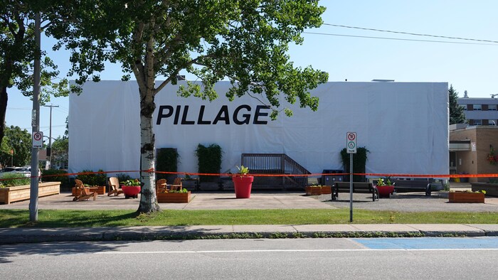 Des bâches blanches recouvrent l'hôtel de ville de Sept-Îles, sur lesquelles est inscrit le mot « pillage ».