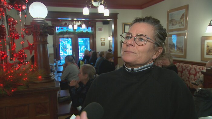 Une femme en entrevue dans un restaurant face à la caméra répond aux questions d'un journaliste.