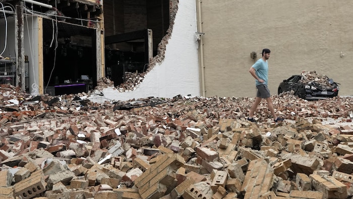 Un homme marche à travers les briques tombées d’un bâtiment endommagé à la suite d’un violent orage.