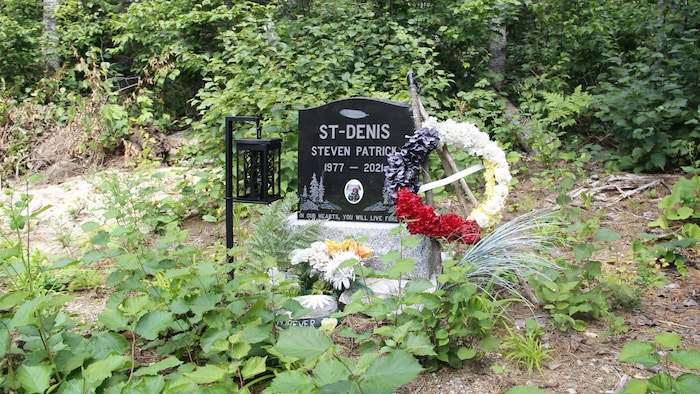 Une tombe avec une couronne de fleurs aux couleurs de la roue de la médecine.