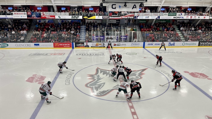10 joueurs de hockey sur la glace lors d'une mise en jeu à l'aréna Glencore.
