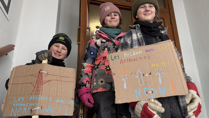 Trois enfants tenant des pancartes.