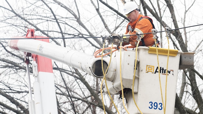Un employé d'Hydro-Québec dans une nacelle travaille à rétablir l'électricité.