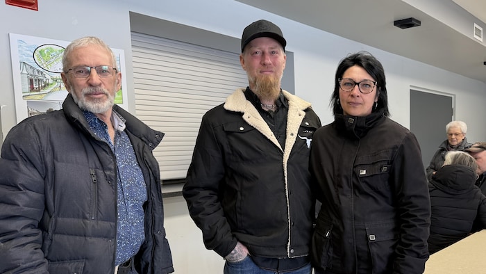 Trois personnes regardent la caméra.