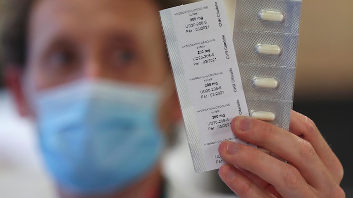 Un pharmacien exhibe les comprimés dans leur emballage.