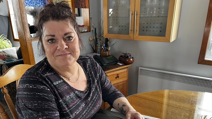 Line Leblanc est assise à sa table de cuisine en bois. Ses mains sont posées sur des documents d'achat et de garantie de son véhicule.