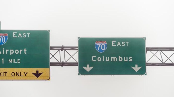 L'affiche verte au-dessus d'une autoroute indiquant l'entrée à Columbus, par une journée brumeuse d'hiver.