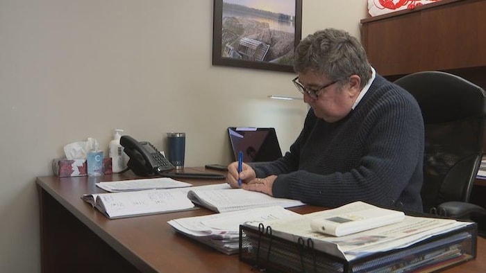 Un homme à son bureau écrit dans un cahier.