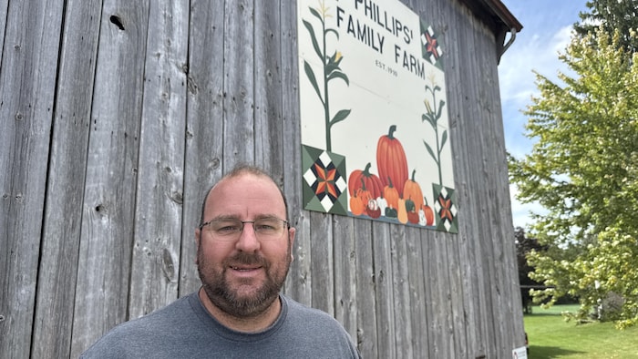 Ian Phillips devant la pancarte de sa ferme «Phillips’ Family Farms».