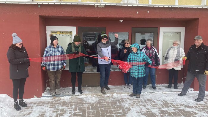 Des habitants d'Ituna, en Saskatchewan, tiennent un ruban devant le bâtiment abritant leur cinéma, le 23 décembre 2025.