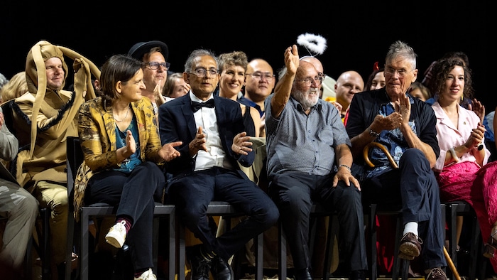 Des personnes assises sur des chaises en train d'applaudir. 