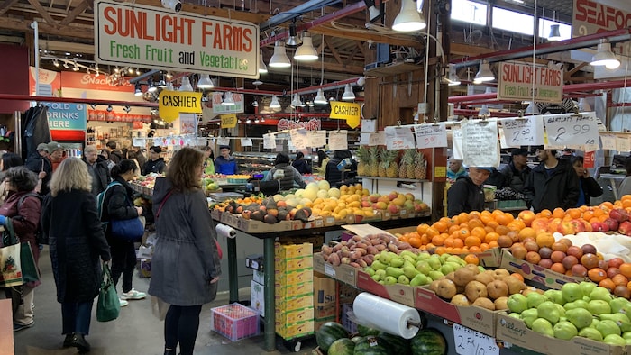 Des clients tournent autour de comptoirs de fruits et de légumes au marché public de l'île Granville.