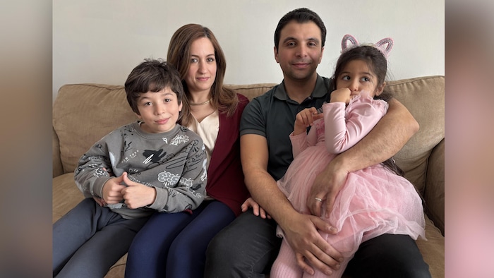 Une famille, deux parents et deux enfants, assis sur un sofa 