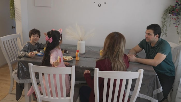 Imane Benchouk, son mari Riyad Boudghene Stambouli et leurs deux enfants âgés de 5 et 9 ans autour d'une table dans la cuisine.