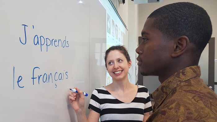 Un élève et son enseignante devant un tableau.