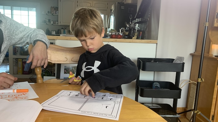 Jacob Gerbrandt colle des lettres sur une feuille.