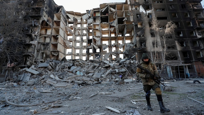 Un homme armé devant un immeuble résidentiel.