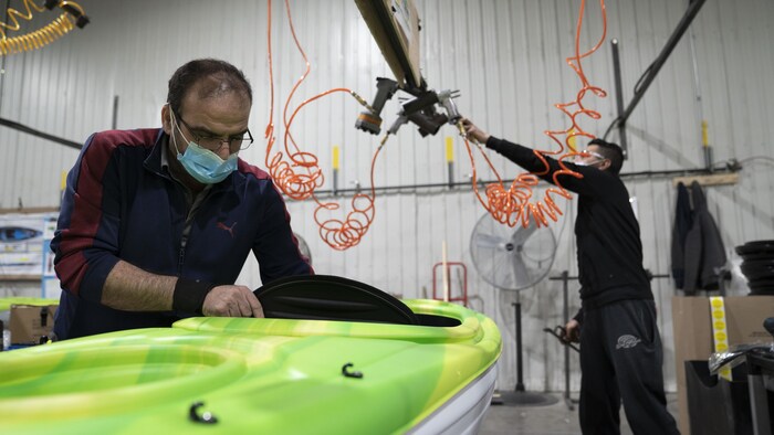 Un travailleur assemble un kayak.