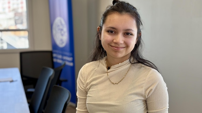 Une jeune femme dans une salle de réunion sourit à la caméra.