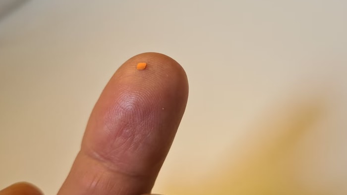 Le nouvel implant oculaire déposé sur le bout du doigt d'une personne.